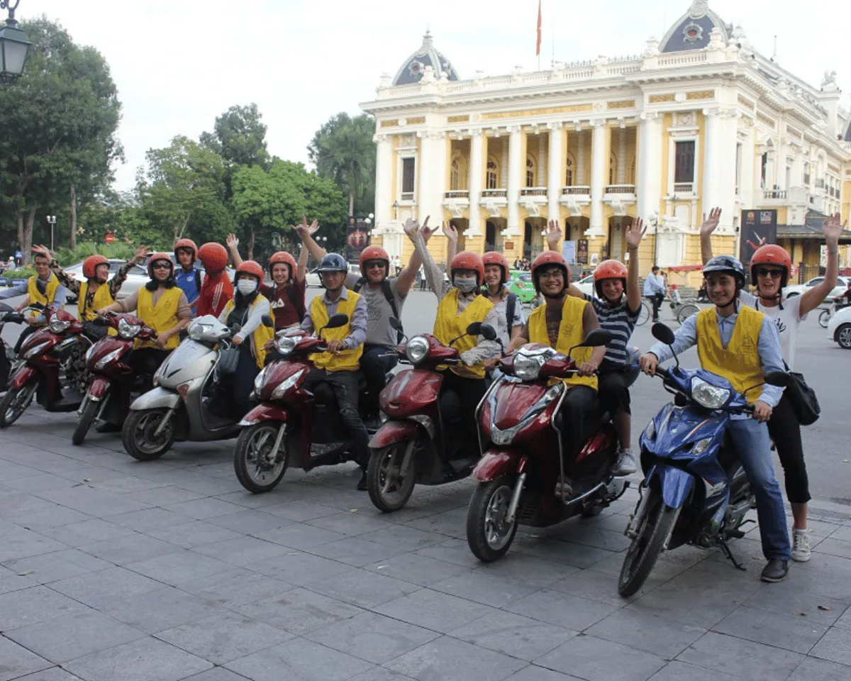 Traveler riding pillion past lit food stalls on a motorbike hanoi food tour at night in Vietnam